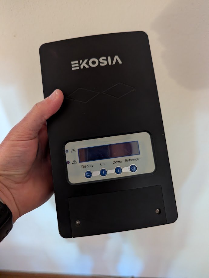 Routeur solaire SmartSun — transformez votre surplus en eau chaude 5 Le boîtier SmartSun tenu dans une main, avant sa pose : format d'un grand smartphone, façade noire, écran de contrôle et quatre boutons.